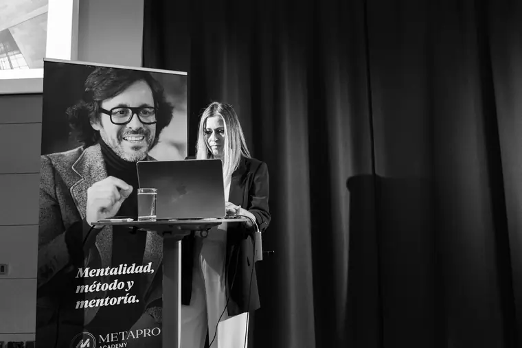 Ponencia en un auditorio a oscuras, con la oradora en el atril y su presentacion proyectada en la pantalla